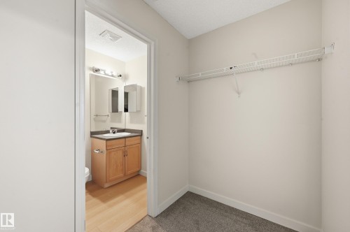 This property features a storage area with a wire shelf, complemented by a bathroom entrance showcasing a vanity with a mirror and lighting - 314 2430 Guardian Road, Edmonton, AB - Indoor