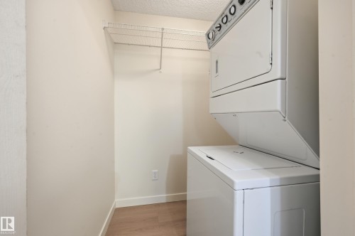 Laundry area featuring a stacked washer and dryer unit, wire shelving, and light-colored flooring - 314 2430 Guardian Road, Edmonton, AB - Indoor Photo Showing Laundry Room
