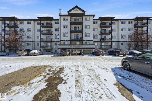 The property features a multi-story building with a light-colored facade and dark trim - 314 2430 Guardian Road, Edmonton, AB - Outdoor With Balcony With Facade