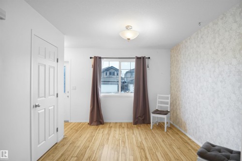 The property features light-toned hardwood flooring, a window with curtains, and a wall adorned with patterned wallpaper - 13 3751 12 Street, Edmonton, AB - Indoor