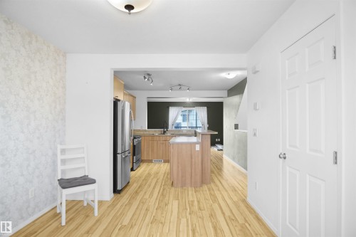 The kitchen features a central island, stainless steel appliances, and wood cabinetry - 13 3751 12 Street, Edmonton, AB - Indoor