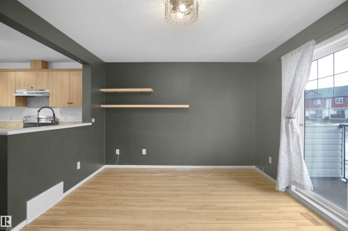 Dining area with hardwood floors, a modern light fixture, and two floating shelves - 13 3751 12 Street, Edmonton, AB - Indoor