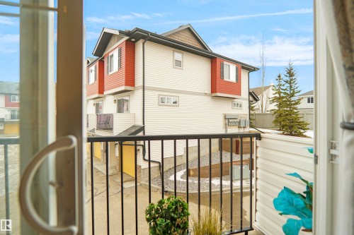 This property features durable vinyl siding, a private balcony with black railings, and an exterior highlighted by a combination of white and red paneling - 13 3751 12 Street, Edmonton, AB -  With Exterior