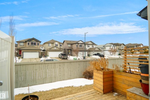 The property features a wooden deck with planter boxes, a wooden fence, and a view of residential homes - 13 3751 12 Street, Edmonton, AB - Outdoor With Deck Patio Veranda