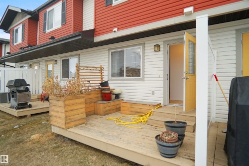 Rear exterior with a wooden deck, a wooden planter box, and a yellow door with glass panels - 13 3751 12 Street, Edmonton, AB - Outdoor With Deck Patio Veranda With Exterior