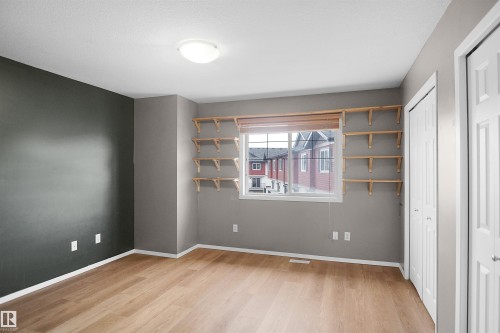 This room features light wood flooring, a window with a wood blind, and a series of wood shelving brackets - 13 3751 12 Street, Edmonton, AB - Indoor Photo Showing Other Room