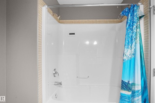 The bathroom features a pristine white shower and tub unit, complete with a shower head and faucet - 13 3751 12 Street, Edmonton, AB - Indoor Photo Showing Bathroom