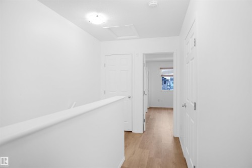 This hallway features light wood-look flooring, white walls, and white paneled doors - 13 3751 12 Street, Edmonton, AB - Indoor Photo Showing Other Room