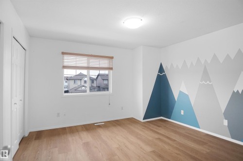 This room features light wood flooring and a wall with a decorative mountain mural - 13 3751 12 Street, Edmonton, AB - Indoor Photo Showing Other Room