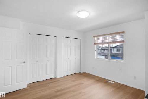 The property features light wood flooring, white walls, and a window with blinds providing views of the surrounding neighborhood - 13 3751 12 Street, Edmonton, AB - Indoor Photo Showing Other Room