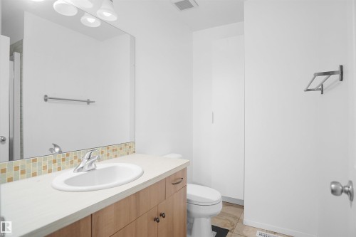 Bathroom featuring a wood vanity with a white countertop, a rectangular sink, and a large mirror - 13 3751 12 Street, Edmonton, AB - Indoor Photo Showing Bathroom