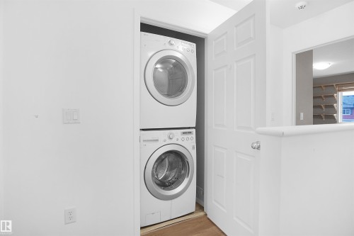 This property features a convenient laundry area with a stacked washer and dryer, situated within a dedicated alcove - 13 3751 12 Street, Edmonton, AB - Indoor Photo Showing Laundry Room