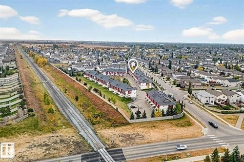 Aerial view of the property and surrounding neighborhood, featuring residential homes with dark roofs and light exteriors, and a road with crosswalk markings - 13 3751 12 Street, Edmonton, AB - Outdoor With View