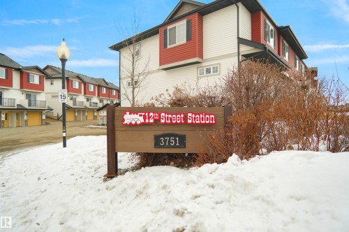 The property features a distinctive red and white facade with dark trim, complemented by a prominent wooden sign indicating its address - 13 3751 12 Street, Edmonton, AB - Outdoor