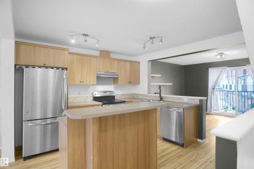 The kitchen features light wood cabinetry, stainless steel appliances, and a breakfast bar - 13 3751 12 Street, Edmonton, AB - Indoor Photo Showing Kitchen With Stainless Steel Kitchen