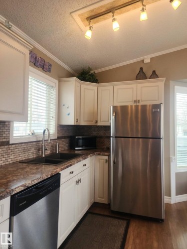 The kitchen features white cabinetry, stainless steel appliances, a tiled backsplash, and track lighting - 46 Willow Park Estates, Leduc, AB - Indoor Photo Showing Kitchen With Double Sink