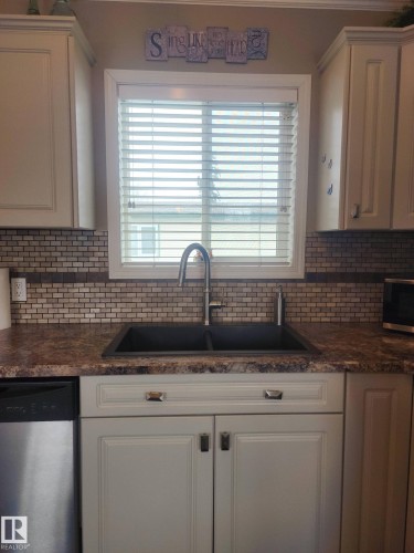 Kitchen featuring light-colored cabinetry, a dual basin sink with a gooseneck faucet, a tile backsplash, and a dishwasher - 46 Willow Park Estates, Leduc, AB - Indoor Photo Showing Kitchen With Double Sink
