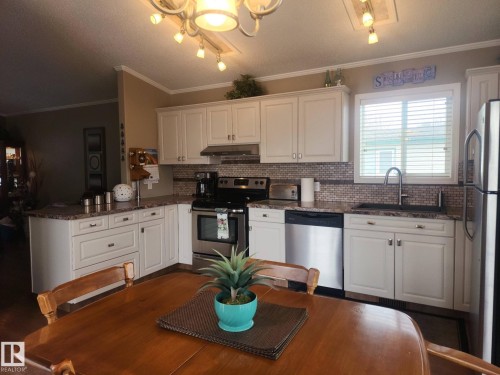 The kitchen features white cabinetry, stainless steel appliances, a tile backsplash, and a window with blinds - 46 Willow Park Estates, Leduc, AB - Indoor Photo Showing Kitchen