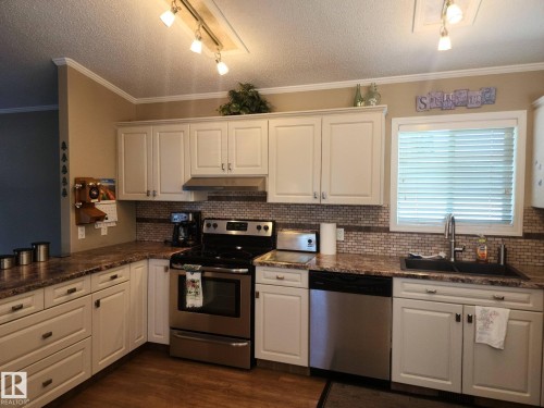Bathroom with a vanity featuring a white sink and a light-colored countertop, white cabinetry with silver-toned hardware, and a toilet - 46 Willow Park Estates, Leduc, AB - Indoor Photo Showing Bathroom