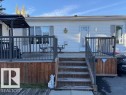 The property features a spacious wooden deck with a dark railing, leading to the entrance of the home - 46 Willow Park Estates, Leduc, AB  - Outdoor With Deck Patio Veranda 