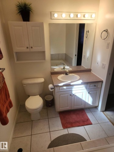 Bathroom featuring a vanity with an integrated sink and cabinet storage, a wall-mounted mirror, and tiled flooring - 46 Willow Park Estates, Leduc, AB - Indoor Photo Showing Bathroom