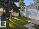 The property features a green lawn, a wooden deck, a mature evergreen tree, and a storage shed - 46 Willow Park Estates, Leduc, AB  - Outdoor 