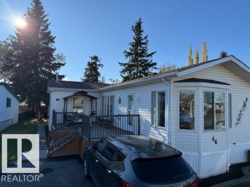 The property features a white exterior with bay windows and a wooden deck - 46 Willow Park Estates, Leduc, AB - Outdoor With Deck Patio Veranda