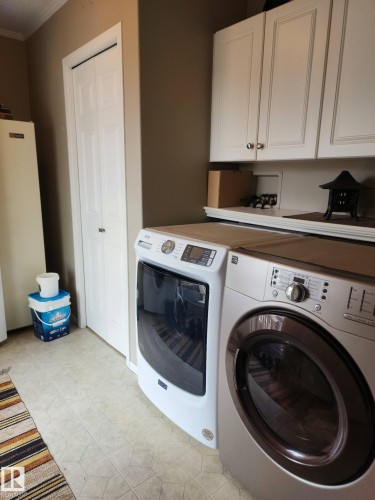 This utility area features white upper cabinetry, a white bi-fold door, and light-colored flooring - 46 Willow Park Estates, Leduc, AB - Indoor Photo Showing Laundry Room