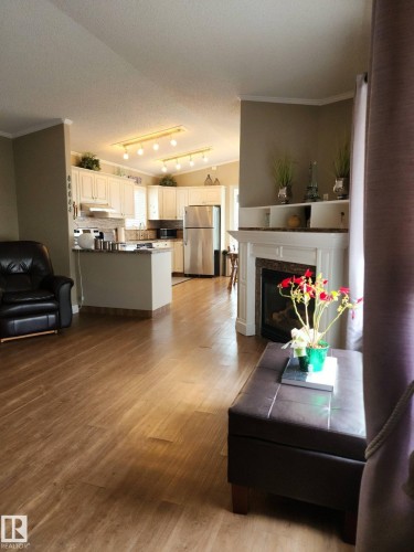 The property features a spacious open-concept living area with wood-look flooring and a fireplace - 46 Willow Park Estates, Leduc, AB - Indoor Photo Showing Living Room With Fireplace