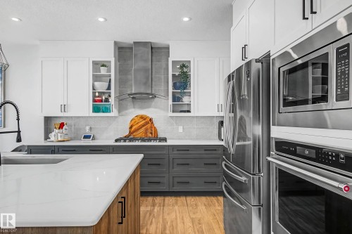 Contemporary kitchen featuring white upper cabinetry, grey lower cabinetry, stainless steel appliances, and light-colored countertops - 34 Riverhill Crescent, St. Albert, AB - Indoor Photo Showing Kitchen With Upgraded Kitchen