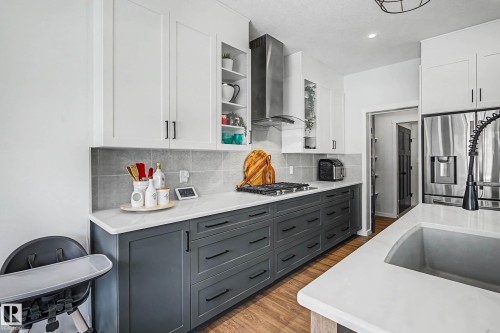 The kitchen features white upper cabinetry, dark lower cabinetry with black hardware, and light-colored countertops - 34 Riverhill Crescent, St. Albert, AB - Indoor Photo Showing Kitchen