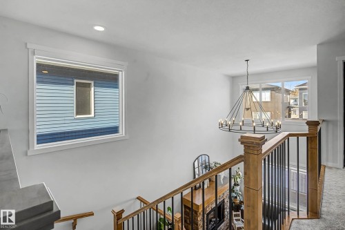 The property features a staircase with wood banisters and black metal spindles, an overhead chandelier, and recessed lighting - 34 Riverhill Crescent, St. Albert, AB - Indoor Photo Showing Other Room