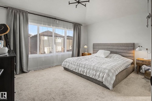 This inviting bedroom features a large window with sheer and blackout curtains, a vaulted ceiling, and light-colored carpeting - 34 Riverhill Crescent, St. Albert, AB - Indoor Photo Showing Bedroom