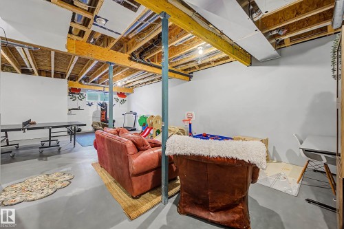The lower level offers a versatile space with painted concrete flooring and an exposed ceiling - 34 Riverhill Crescent, St. Albert, AB - Indoor Photo Showing Basement