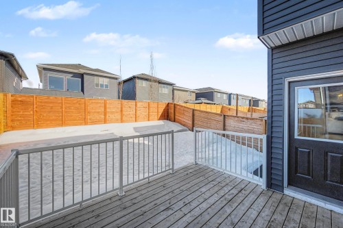 The property features a wooden deck with a metal railing, a dark exterior with horizontal siding, and a back door with a window - 34 Riverhill Crescent, St. Albert, AB - Outdoor With Exterior