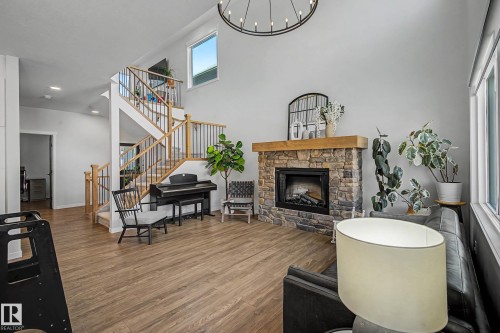 This living area features a stone fireplace with a wooden mantle, high ceilings, and hardwood floors - 34 Riverhill Crescent, St. Albert, AB - Indoor With Fireplace