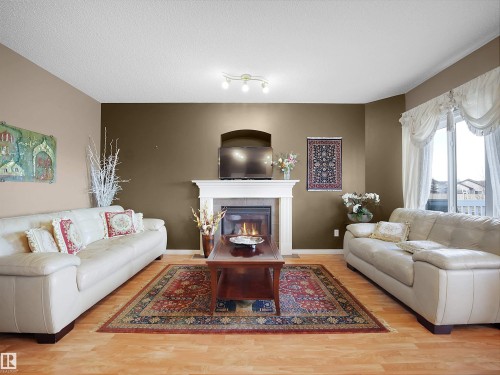 Living area featuring a tiled fireplace, light wood finished floors, and a textured ceiling - 11708 10 Avenue, Edmonton, AB - Indoor Photo Showing Living Room With Fireplace