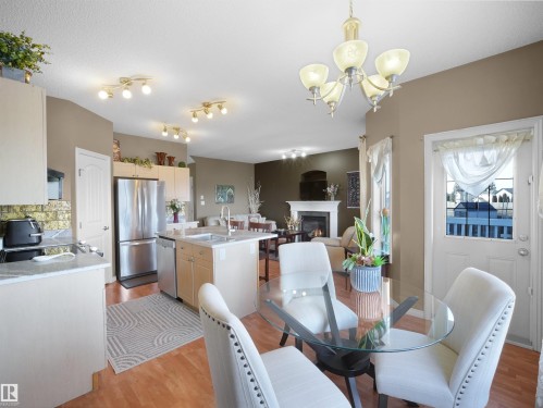 Dining space with light wood finished floors, a glass covered fireplace, and hanging lights - 11708 10 Avenue, Edmonton, AB - Indoor Photo Showing Dining Room