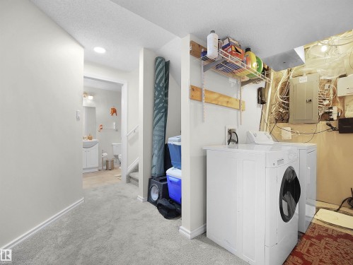 Laundry area with electric panel, light carpet, separate washer and dryer, and a textured ceiling - 11708 10 Avenue, Edmonton, AB - Indoor Photo Showing Laundry Room