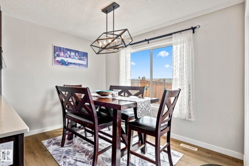 Dining area featuring a contemporary geometric chandelier, a window with lace curtains, and light-colored walls - 483 Ebbers Way Nw, Edmonton, AB - Indoor Photo Showing Dining Room