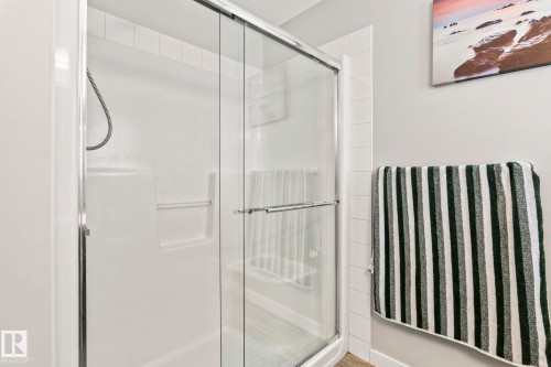 Bathroom featuring a shower with a sliding glass door and white tiled walls - 483 Ebbers Way Nw, Edmonton, AB - Indoor Photo Showing Bathroom