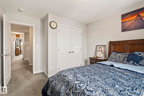 This room features carpeted flooring, a white paneled closet, and a wooden bed frame - 483 Ebbers Way Nw, Edmonton, AB - Indoor Photo Showing Bedroom
