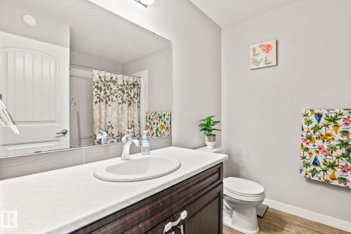 Bathroom featuring a vanity with a white countertop and a dark wood-look cabinet, a white toilet, and light-colored walls - 483 Ebbers Way Nw, Edmonton, AB - Indoor Photo Showing Bathroom