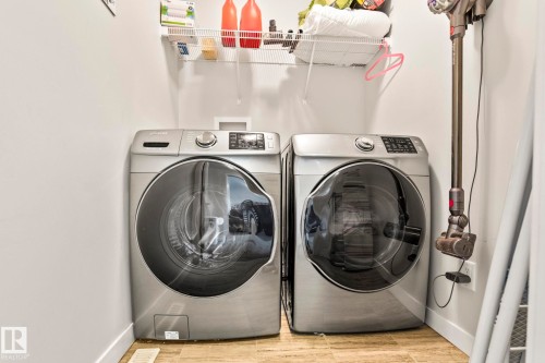 Dedicated laundry area featuring a washer and dryer, complete with overhead shelving for storage - 483 Ebbers Way Nw, Edmonton, AB - Indoor Photo Showing Laundry Room