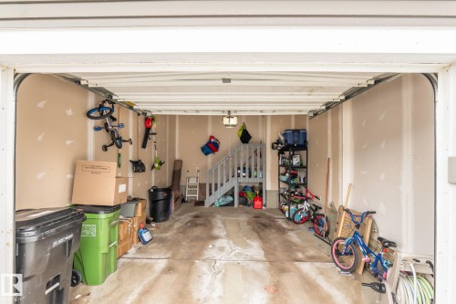 The property includes a spacious garage with unfinished walls, a concrete floor, and a visible staircase providing access to an additional area - 483 Ebbers Way Nw, Edmonton, AB - Indoor Photo Showing Garage