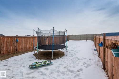 The property features a fenced yard with a combination of snow-covered ground and visible dry patches - 483 Ebbers Way Nw, Edmonton, AB - Outdoor
