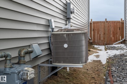 The property features horizontal siding, a visible air conditioning unit, and a wooden fence - 483 Ebbers Way Nw, Edmonton, AB - Outdoor