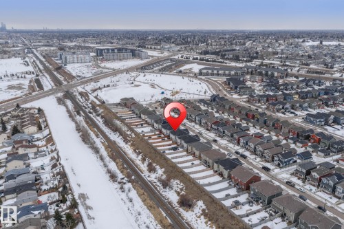 Aerial view showcasing a residential area featuring detached homes and townhomes, with nearby transportation infrastructure - 483 Ebbers Way Nw, Edmonton, AB - Outdoor With View