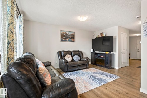 Inviting living area featuring light-colored walls, wood-look flooring, and a decorative area rug - 483 Ebbers Way Nw, Edmonton, AB - Indoor Photo Showing Living Room