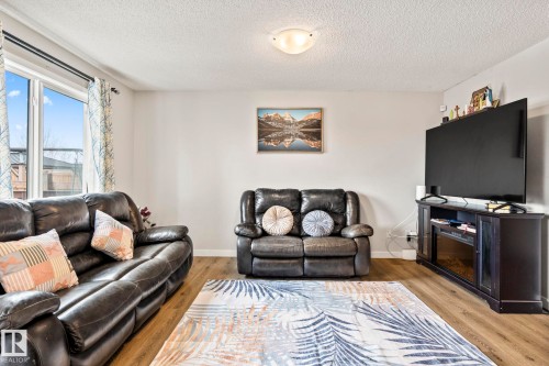 The living area features light-colored walls, a large window, and light wood flooring - 483 Ebbers Way Nw, Edmonton, AB - Indoor Photo Showing Living Room